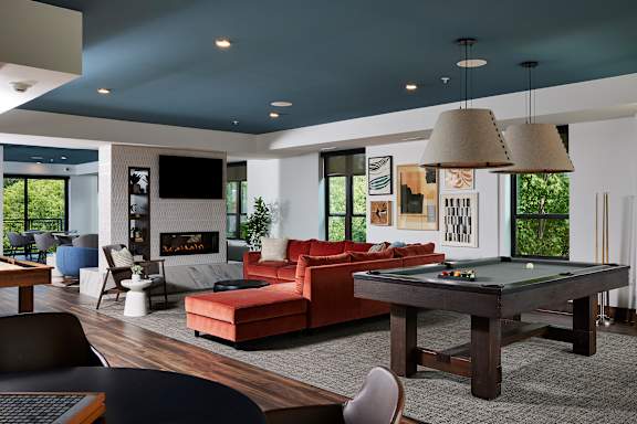 A modern living room with a pool table and a fireplace.