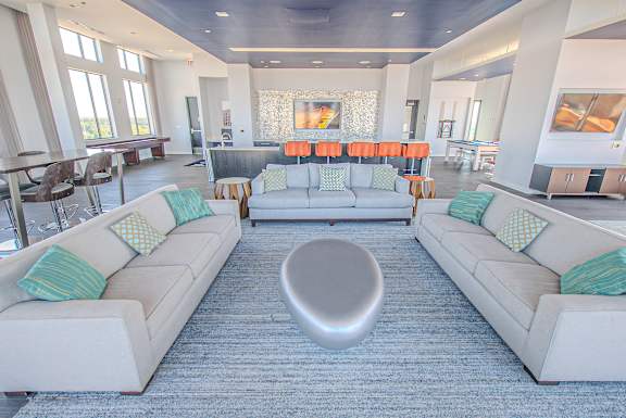 A large, modern living room with two white couches and a grey ottoman.