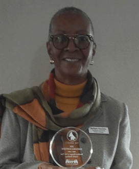 a woman wearing glasses and a scarf and holding a medal