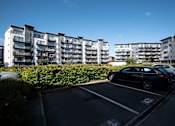 Thumbnail 2 of 5 - a parking lot with cars in front of an apartment building