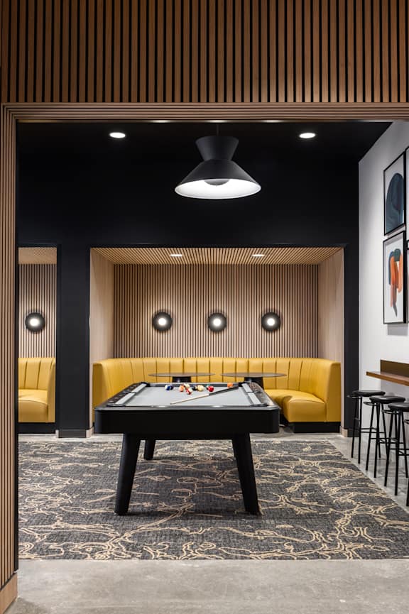 A room with a pool table and a yellow couch.