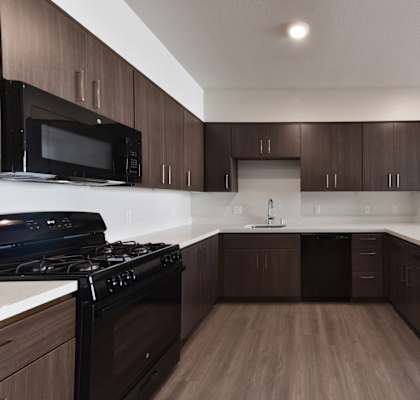 A kitchen with dark brown cabinets and a black stove top oven.