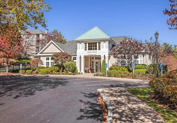 A large building with a green roof and a driveway in front.