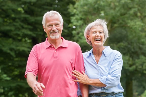 an older couple walking down a path in the park