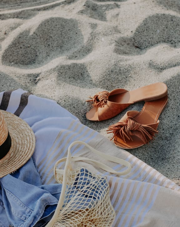 a straw hat and a blue blanket on the beach
