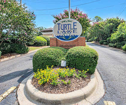 a sign for turtle creek apartments with an flag in front of the street