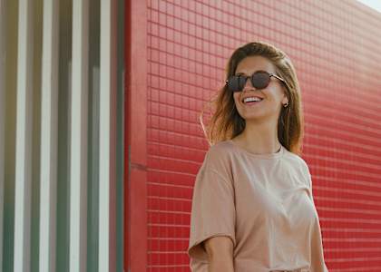 a woman standing in front of a red wall holding a skateboard