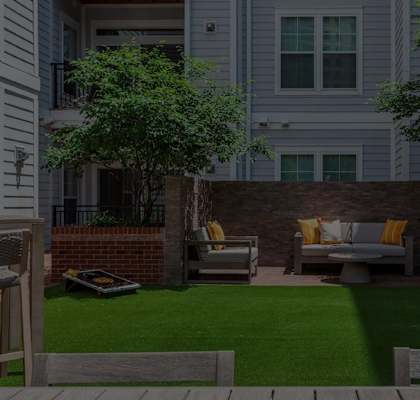 a patio with chairs and a lawn in front of a house