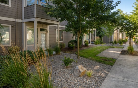 a front yard with a tree and a stone in front of a house