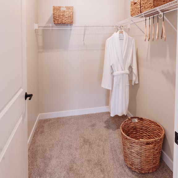 a walk in closet with a white robe and a basket