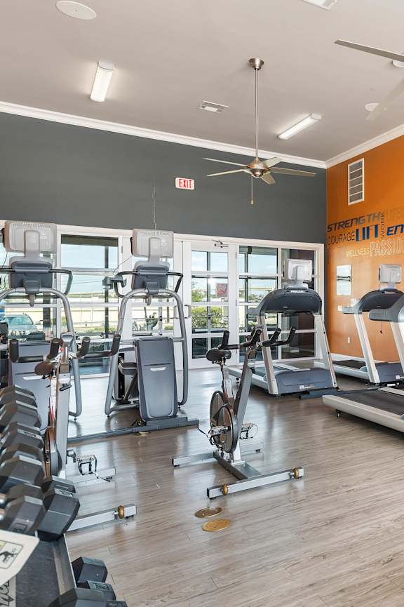 A gym with a variety of equipment including treadmills, weights, and exercise machines.