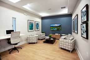 A room with a desk, chairs, and a television.