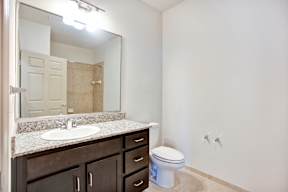 A bathroom with a sink, toilet and mirror.