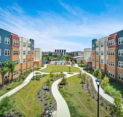 an aerial view of a park and path in front of a row of apartment buildings