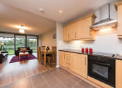 Thumbnail 2 of 3 - a kitchen with wooden cabinets and a stove and a table with chairs