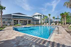 A swimming pool surrounded by palm trees and a building in the background.