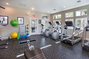 A gym with a variety of equipment including treadmills, exercise balls, and weights.
