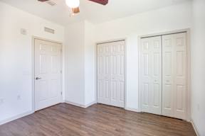 Three white doors in a room with wood floors and a ceiling fan.