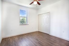 A room with a white door and a window with a view of trees outside.