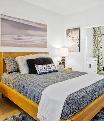 A bedroom with a large bed, a nightstand, and a painting on the wall.