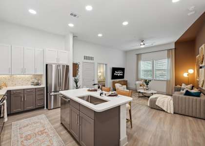 an open kitchen and living room with a sink and a refrigerator