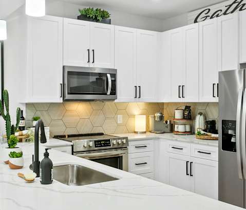 A kitchen with white cabinets and a stainless steel refrigerator.