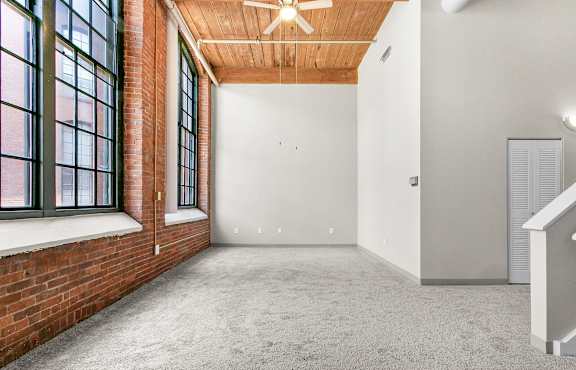 an empty room with three windows and a ceiling fan at Clocktower and Velvet Mill Apartments, Connecticut, 06040