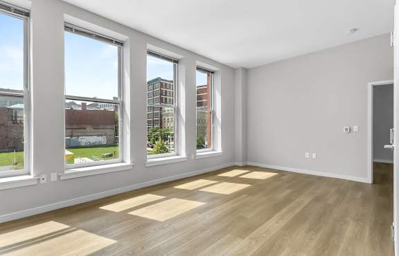 a living room with a wood floor and four windows at 1188 Lofts in Bridgeport, CT, 06604