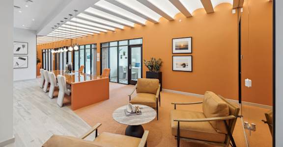 a living room with orange walls and chairs and a table