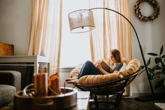 a woman sitting in a chair reading a book in a living room