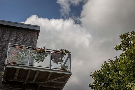 a house with flowers on the balcony and clouds in the sky