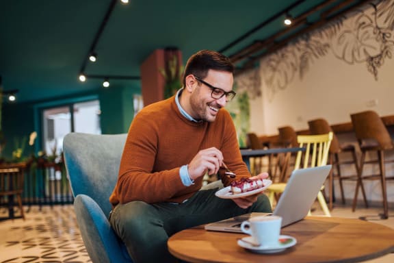 a man sitting at a table with a plate of food and a laptop