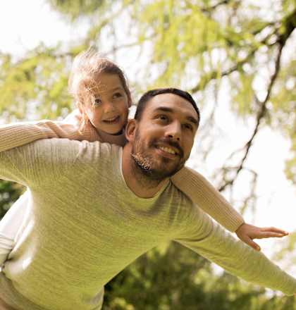 a man carrying a little girl on his shoulders