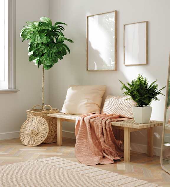 A grey couch sits next to a small table with a potted plant on it.