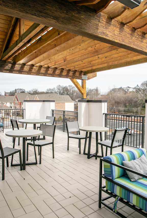 A wooden patio with a striped couch and chairs.