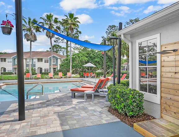 A pool area with a wooden deck and red chairs. at Country Club Lakes, Jacksonville, Florida