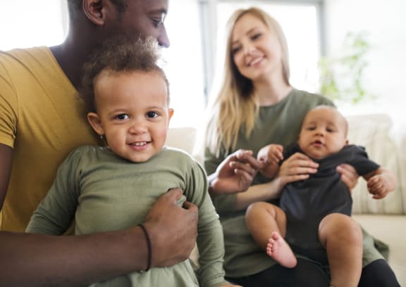 a family sitting on a couch holding two babies