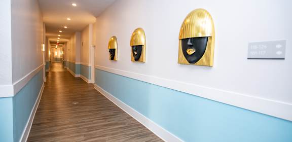 A long hallway with golden framed art on the wall.