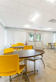 a room with white walls and yellow chairs and tables