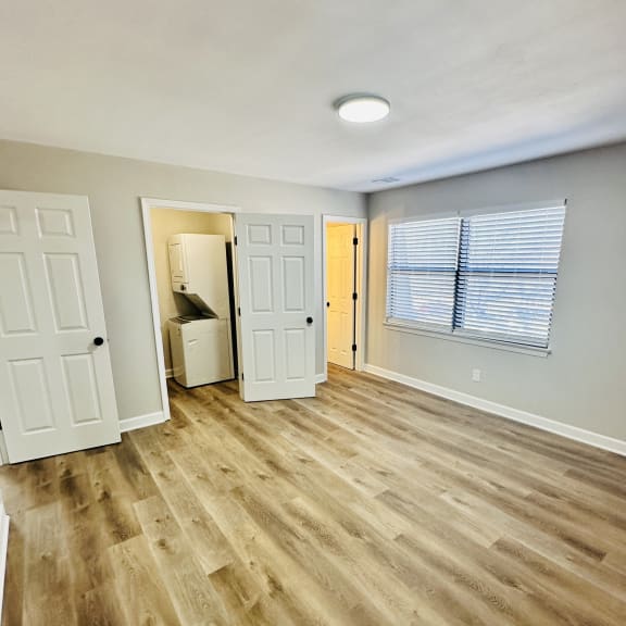 an empty living room with wood flooring and a door to a bathroom