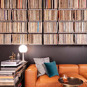 A living room with a leather couch, a table with a candle, and a wall of records.
