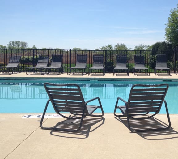 a pair of chaise lounges in front of a swimming pool at The Sanctuary of Lake Villa, Lake Villa, IL