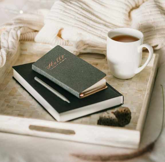 A tray with a book, a cup of coffee, and a brush on it.