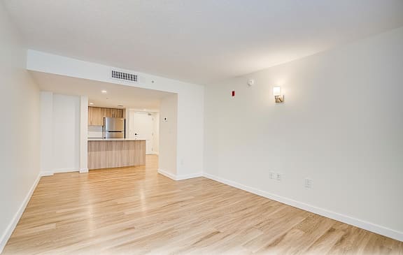 the living room and kitchen of an apartment with wood flooring  at Palm Gardens @ Biscayne Gardens, North Miami, FL