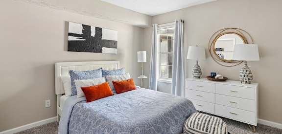 A bedroom with a bed, nightstand, and a painting on the wall.