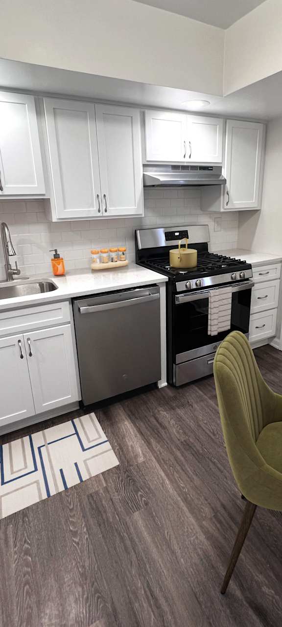 A kitchen with a green chair and a stove top oven.