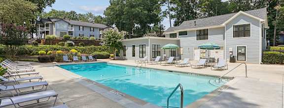 A swimming pool surrounded by lounge chairs and trees.
