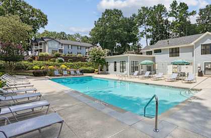 A swimming pool surrounded by lounge chairs and trees.