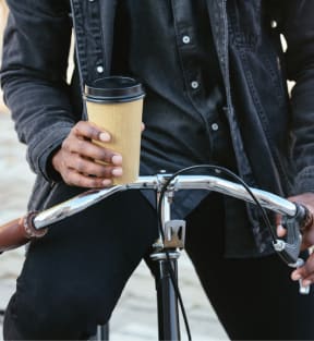 a person sitting on a bike holding a cup of coffee