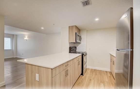 a kitchen with an island and a stainless steel refrigerator  at Palm Gardens @ Biscayne Gardens, North Miami, FL